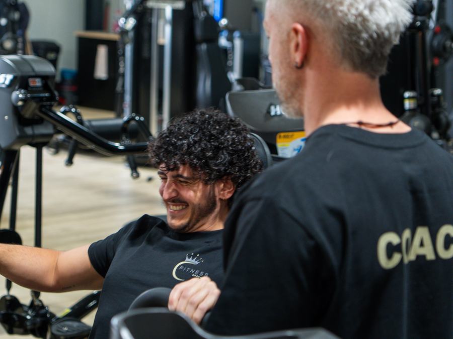 Un coach de C-Fitness Barchon accompagne un membre sur une machine